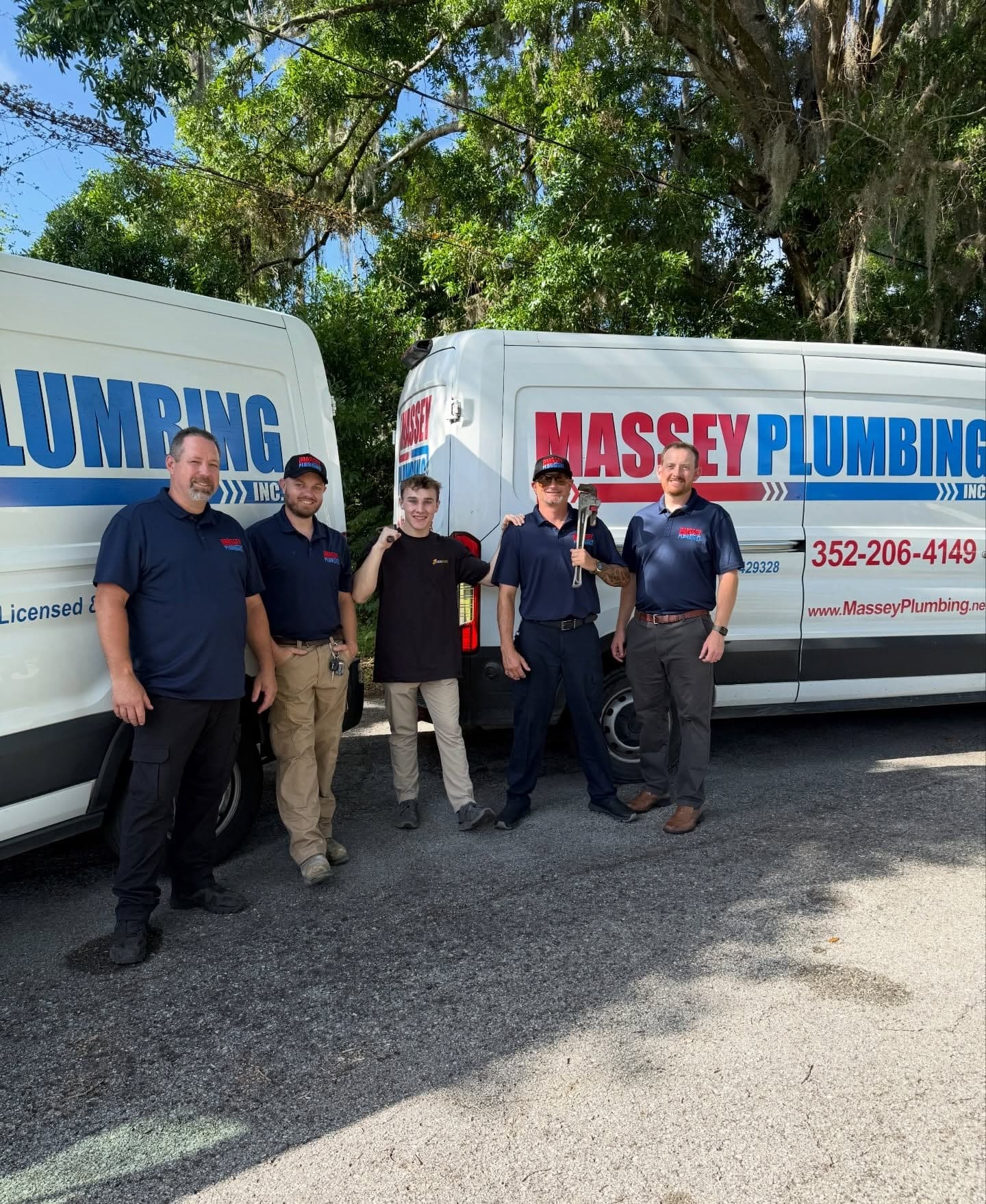 A local plumbing company crew standing in front of their branded service vans