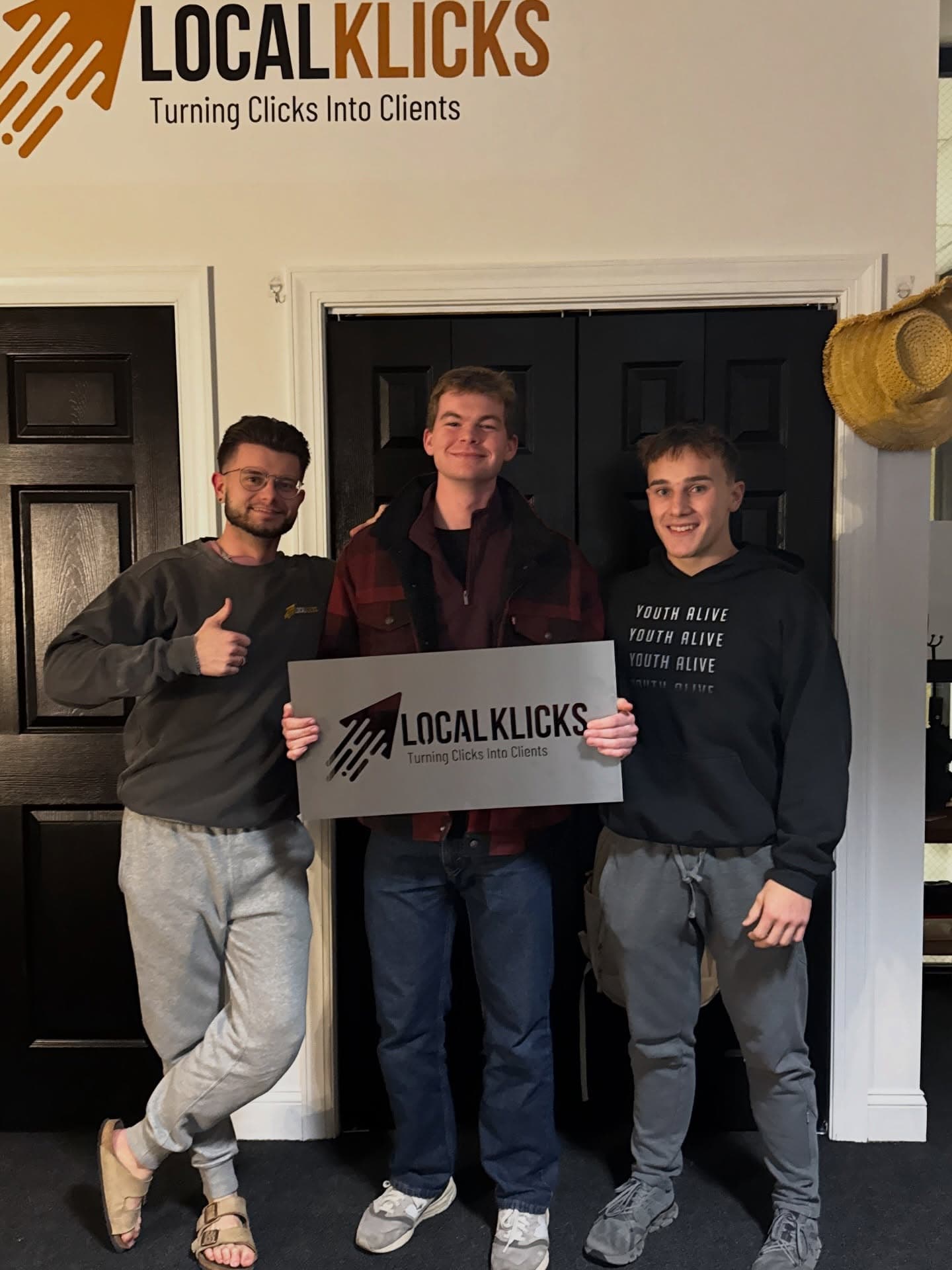 Sean Hodel with Local Klicks teammates holding a Local Klicks sign under the logo in the office