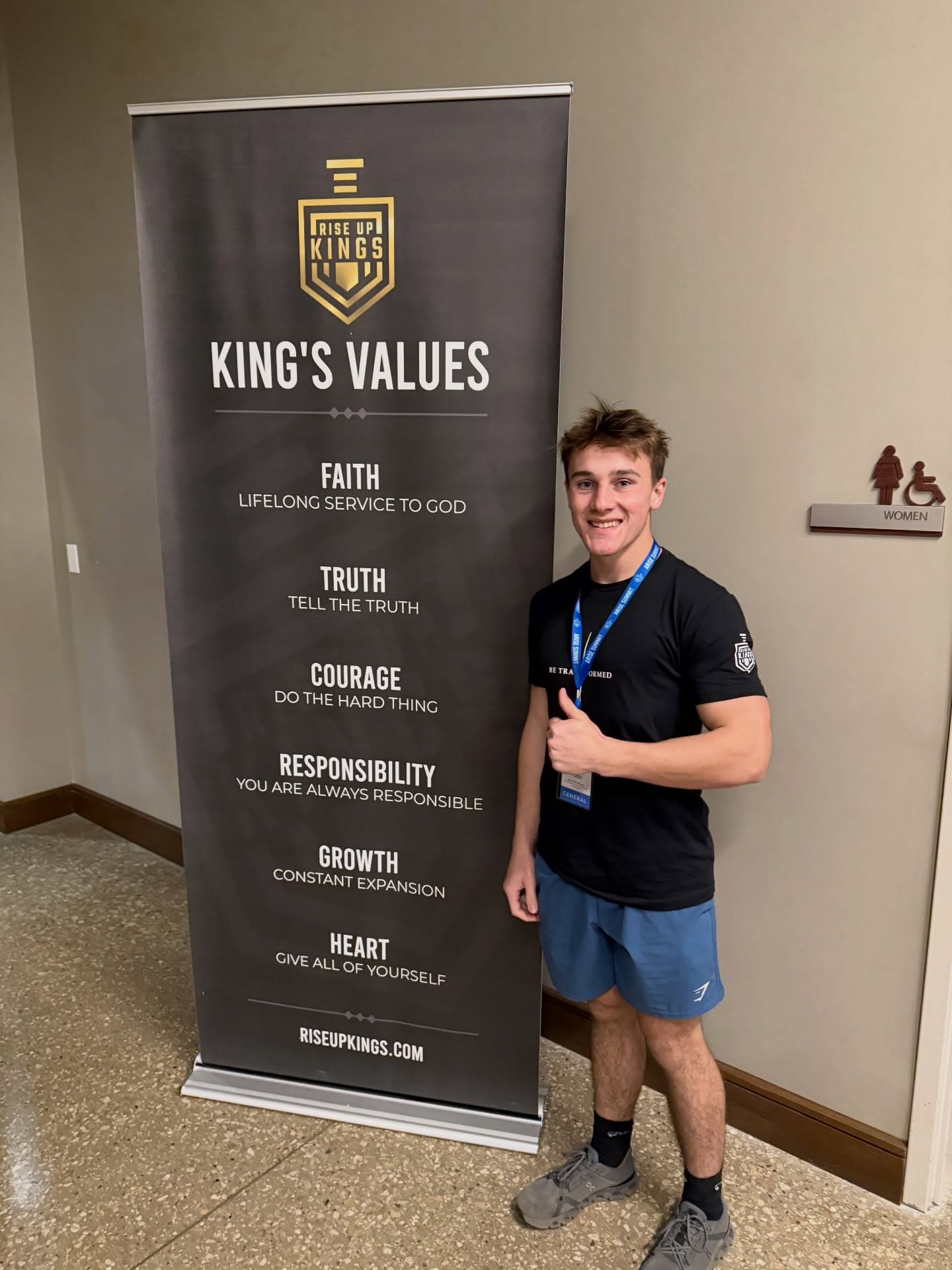 Sean Hodel attending Rise Up Kings in Dallas, next to the King's Values banner