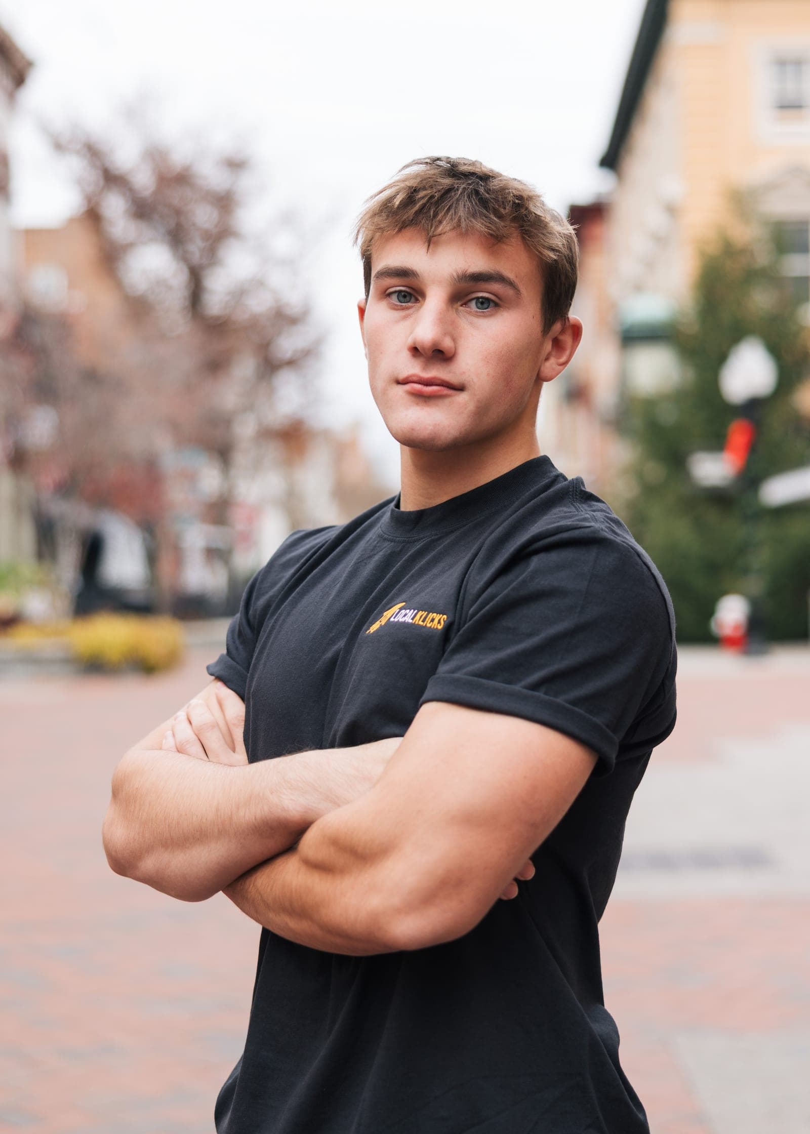 Sean Hodel, arms crossed in a black Local Klicks shirt, on the Old Town walking mall in Winchester, Virginia